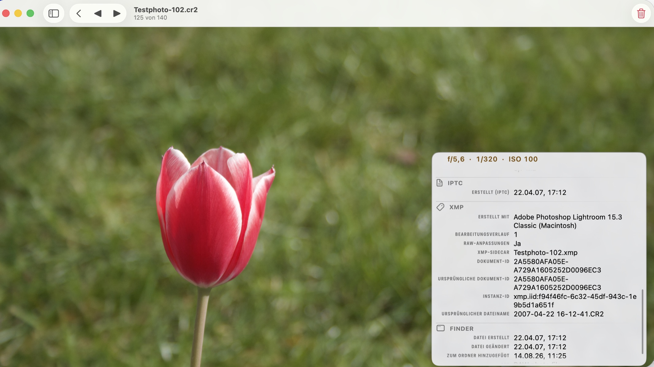 Eine rot-wei&szlig;e Tulpe vor unscharfem Gras, auf dem Mac in PhotoView aus der Canon RAW Datei Testphoto-102.cr2 ge&ouml;ffnet, mit dem Metadaten-Overlay rechts und der Gruppe XMP: erstellt mit Adobe Photoshop Lightroom 15.3 Classic, ein Bearbeitungsschritt, RAW-Anpassungen und die XMP-Sidecar-Datei Testphoto-102.xmp